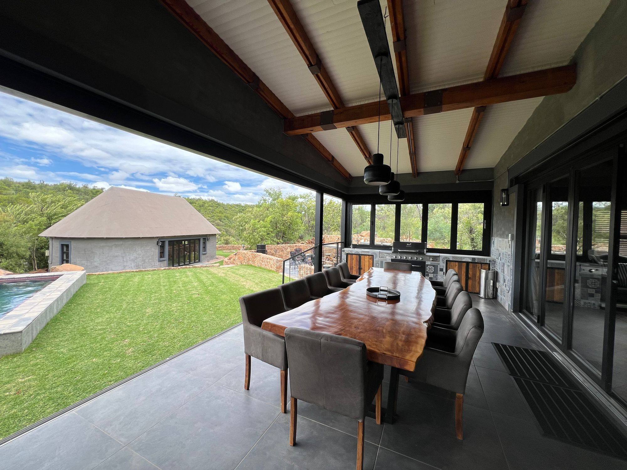 Open-air dining deck at a JVZ Safaris lodge overlooking the bushveld and pool