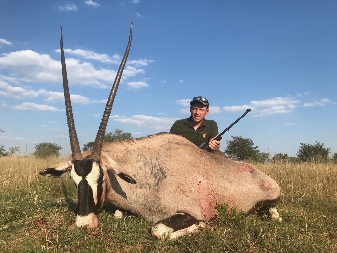 Hunter with a gemsbok in open grassland
